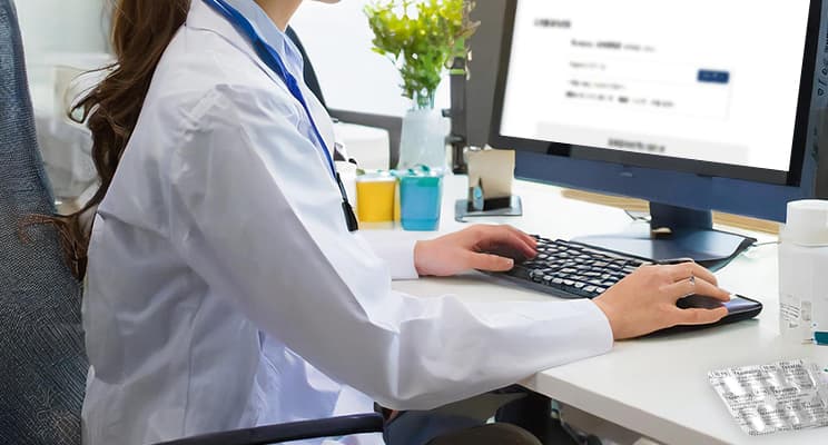 薬を見ながら検索をする医師